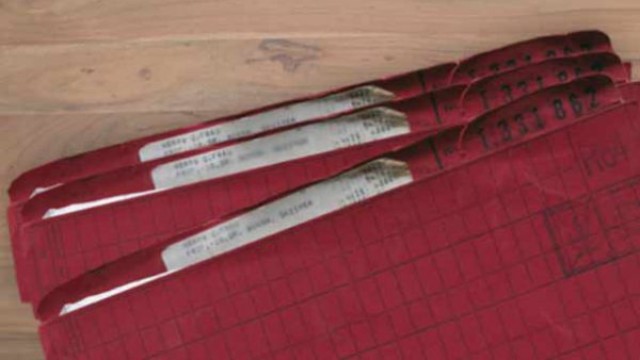 Die Akten der prominenten Bausparer:innen hoben sich von denen der anderen ab Drei purpurrote Akten auf einem holzfarbenen Untergrund